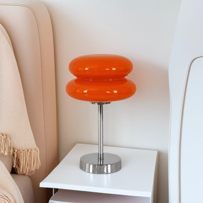 Retro Sandwich Glass Table Lamp placed on a white nightstand next to a beige upholstered chair.