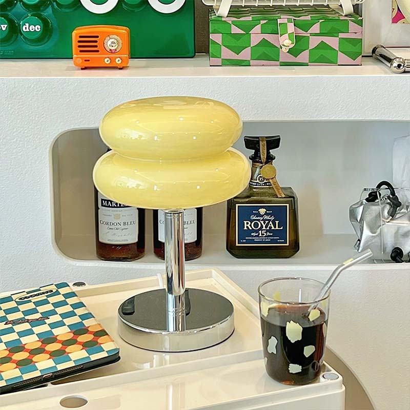Retro Sandwich Glass Table Lamp on a shelf, next to bottles and a glass with dark liquid.