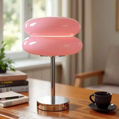 Retro Sandwich Glass Table Lamp placed on a wooden table next to a black coffee cup and books.