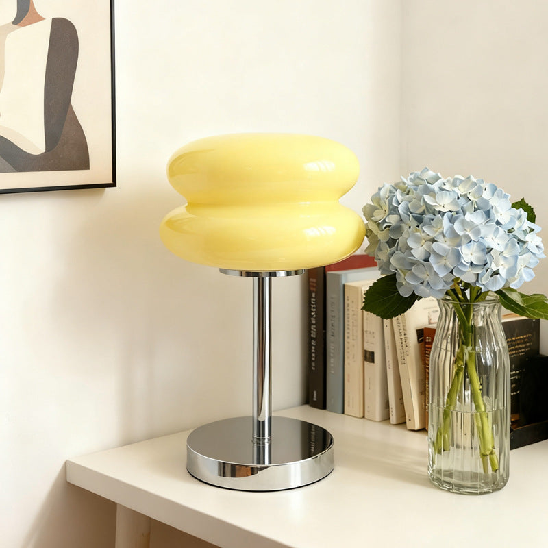 Retro Sandwich Glass Table Lamp placed on a white shelf next to a vase of blue hydrangeas and books.