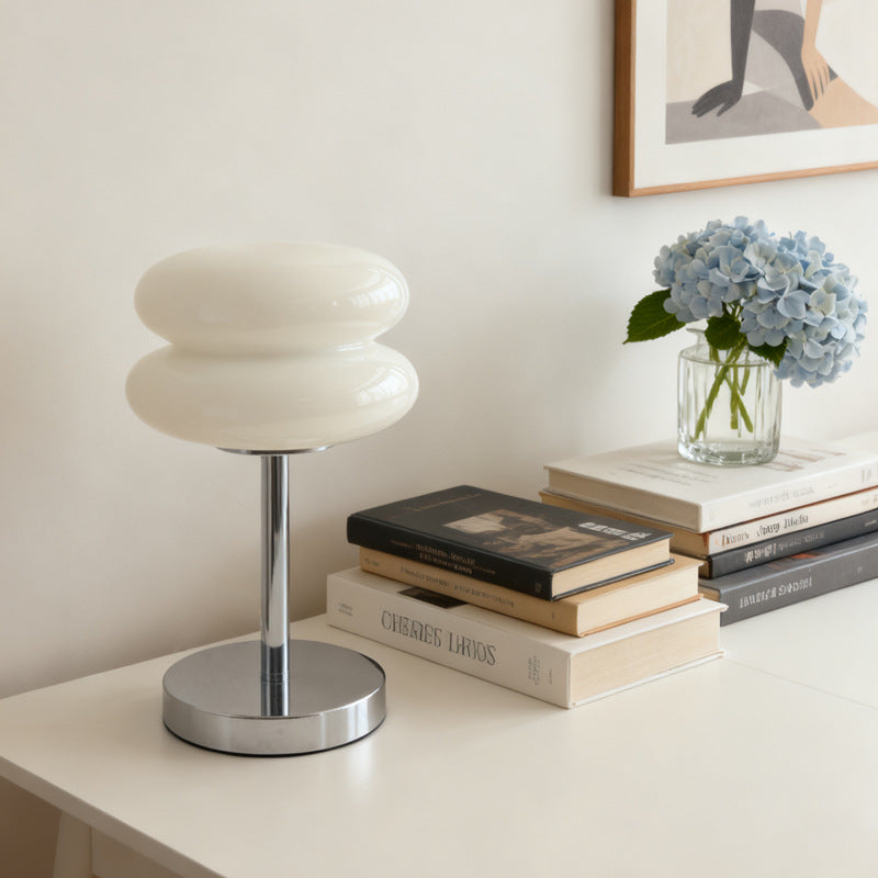 Retro Sandwich Glass Table Lamp shown on a white table next to books and a vase of blue hydrangeas.
