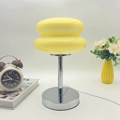 Retro Sandwich Glass Table Lamp placed on a white surface next to a vintage alarm clock and a yellow vase of flowers.