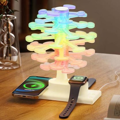 The Spiral Tree LED Desk Lamp, which charges a smartphone and smartwatch, is shown on a wooden table. The lamp shimmers with rainbow colors.
