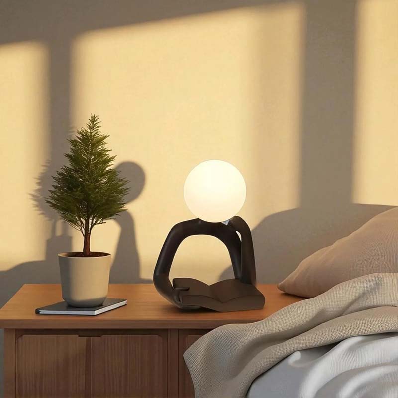 Thinker Statue LED Table Lamp, standing on a wooden nightstand.