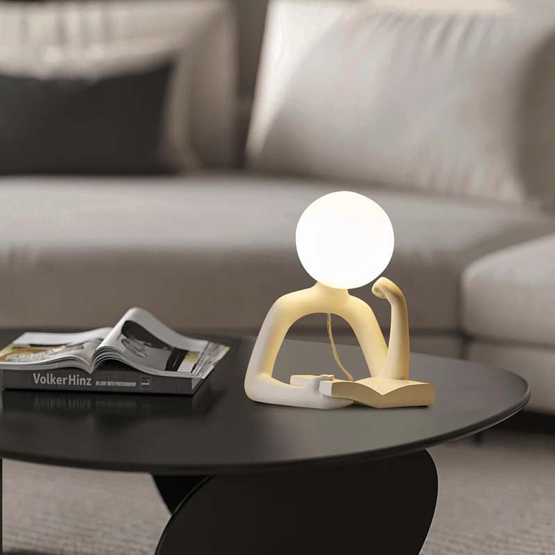 Thinker Statue LED Table Lamp, sits on a dark round coffee table in the living room