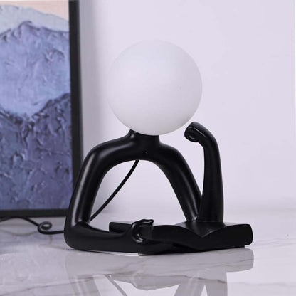 The Thinker Statue LED Table Lamp stands on a glossy white surface against a blurred interior background.