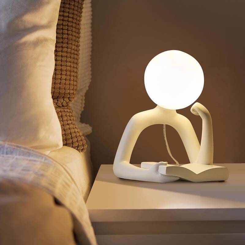 Thinker Statue LED Table Lamp, standing on a nightstand next to the bed.