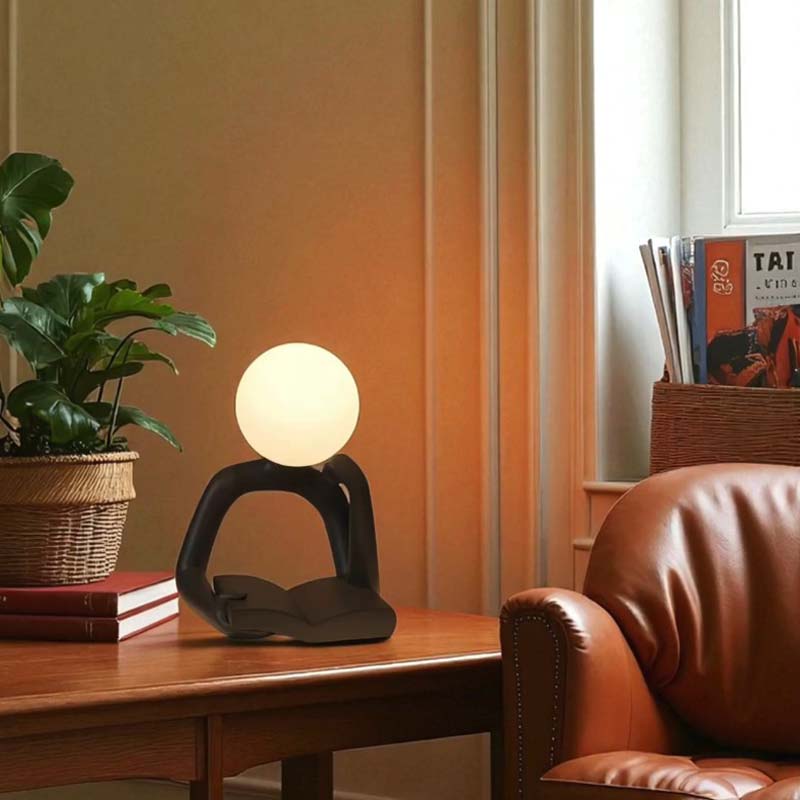 Thinker Statue LED Table Lamp, sitting on a wooden side table in a cozy, stylish room.