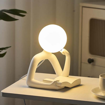 Thinker Statue LED Table Lamp, standing on a light-colored table.