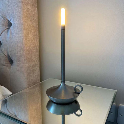 Modern table lamp with a reflective base on a surface.