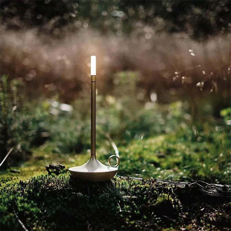 Candlestick with a lit candle on a mossy surface in a forest setting