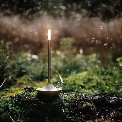 Candlestick with a lit candle on a mossy surface in a forest setting