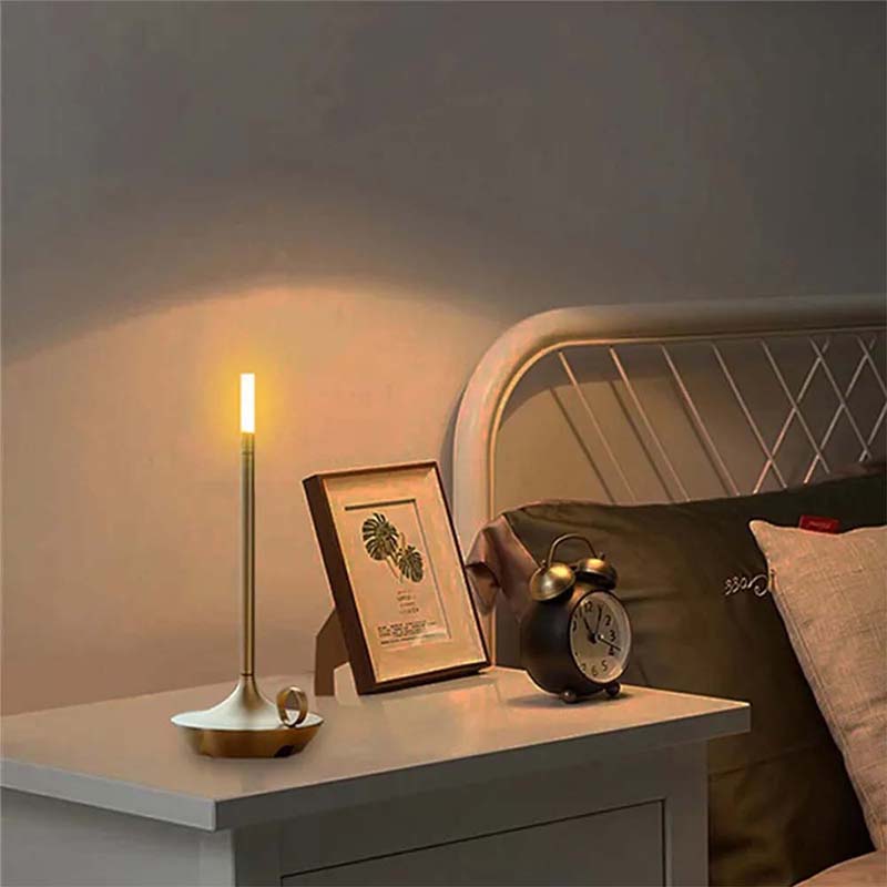 Nighstand with candle, clock, and framed picture in a dimly lit room.