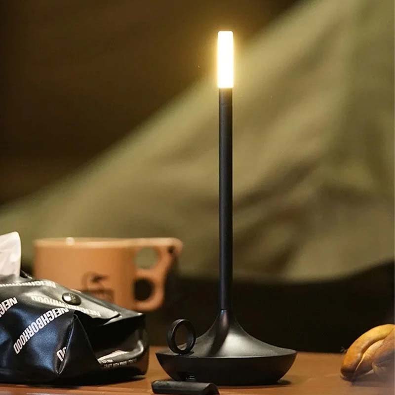 Black candle-shaped lamp on a table with a blurred background