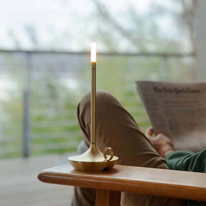 Person reading a newspaper with a lit candle on a table in a blurred indoor setting