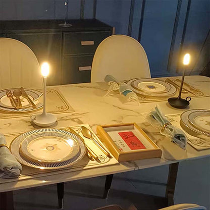 Dining table set with plates, cutlery, and candles in a dimly lit room.