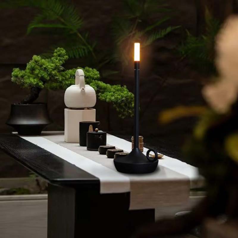 Tea ceremony setup with teapots, cups, and a candle on a table.