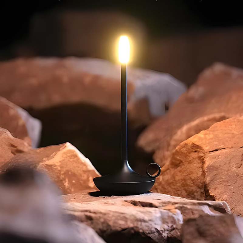 Black lantern with a flame on a rocky surface