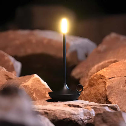 Black lantern with a flame on a rocky surface