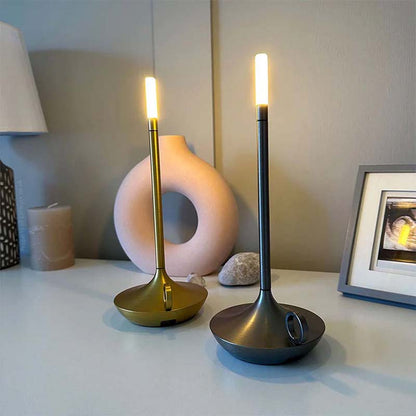 Two candlestick lamps, one gold and one black, on a surface with a neutral background.
