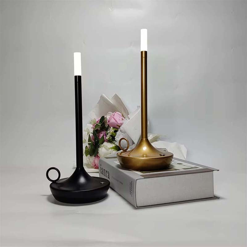 Two candle-shaped lamps, one black and one gold, on a white surface with a light gray background.