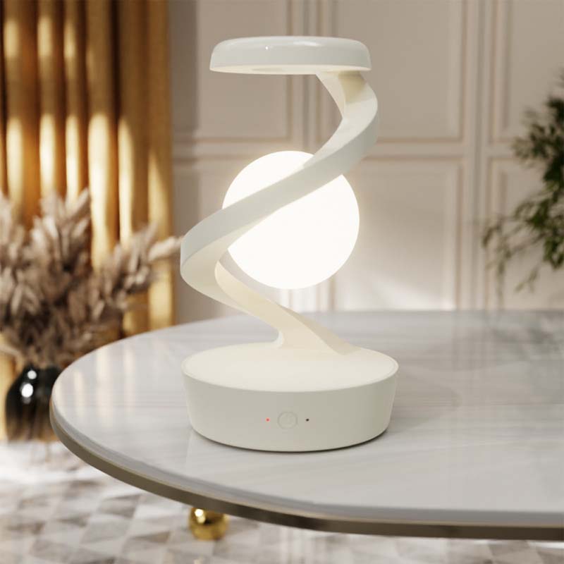 Saturn Helix – LED Desk Lamp with Wireless Charging on a marble surface with decorative elements in the background.