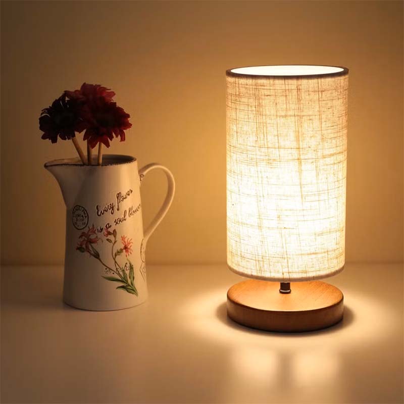 Wood Table Lamp with Natural Fabric Shade on a table next to a decorated vase and flowers