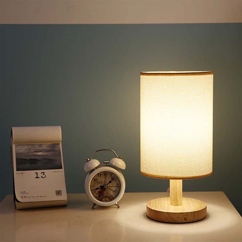 Wood Table Lamp with Natural Fabric Shade on a table next to a clock and calendar