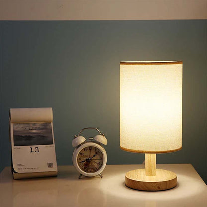 Wood Table Lamp with Natural Fabric Shade on a table next to a clock and calendar