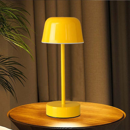 A yellow Rechargeable Cordless Touch LED Table Lamp sits on a round wooden table in front of brown curtains.